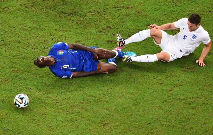 Italy's Mario Balotelli falls after being tackled by England's Gary Cahill (R) during their 2014 World Cup Group D soccer match at the Amazonia arena in Manaus June 14, 2