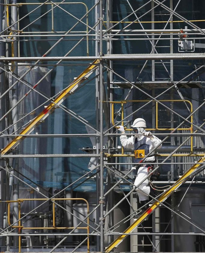 A worker wearing protective suit and mask climbs a scaffolding of the construction site of the multi-nuclide removal facility at Tokyo Electric Power Co. (TEPCO)'s tsunami-crippled Fukushima Daiichi nuclear power plant in Fukushima prefecture, March 6, 2013, ahead of the second-year of anniversary of the the March 11, 2011 tsunami and earthquake. REUTERS/Issei Kato (JAPAN - Tags: DISASTER ANNIVERSARY BUSINESS CONSTRUCTION ENERGY) Published: Bře. 6, 2013, 10:54 dop.