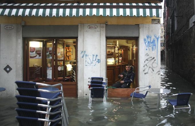 A man rests in a shop in a flooded street during a period of seasonal high water in Venice November 11, 2012. The water level in the canal city rose to 149 cm (59 inches) above normal, according to local monitoring institute Center Weather Warnings and Tides. REUTERS/Manuel Silvestri (ITALY - Tags: ENVIRONMENT SOCIETY) Published: Lis. 11, 2012, 1:57 odp.