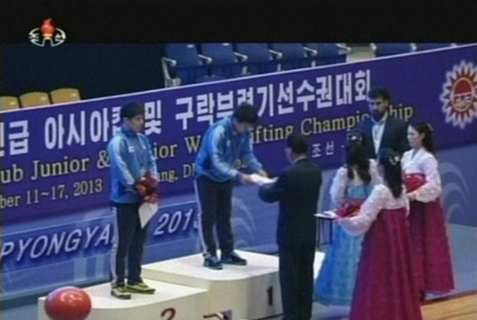 South Korean weightlifters Lee Young-gyun (L) stands as Kim Woo-sik (C) receives his award on the podium during their medal ceremony as part of the Asian Cup and Interclu