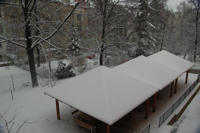 V Dejvicích sněží i krátce po jedné hodině odpoledne, kdy byla fotografie pořízena.