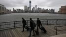 The skyline of New York's Lower Manhattan and One World Trade Center are seen while people pull their luggage at Waterfront in New Jersey, October 28, 2012. Tens of millions of East Coast residents scrambled on Sunday to prepare for Hurricane Sandy, which could make landfall as the largest storm to hit the United States, bringing battering winds, flooding and even heavy snow. REUTERS/Eduardo Munoz (UNITED STATES - Tags: ENVIRONMENT DISASTER)