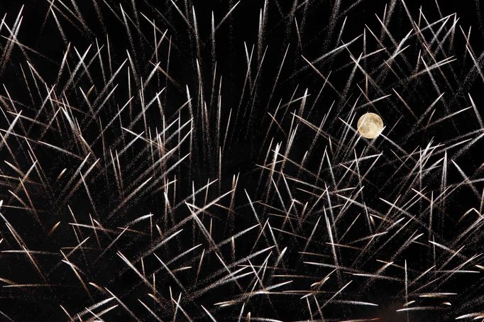 Fireworks streak past in front of the supermoon outside the town of Mosta, celebrating the feast of its patron saint, in central Malta