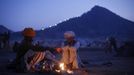 Camel herders warm themselves by a fire at Pushkar Fair in the desert Indian state of Rajasthan November 23, 2012. Many international and domestic tourists throng to Pushkar to witness one of the most colourful and popular fairs in India. Thousands of animals, mainly camels, are brought to the fair to be sold and traded. REUTERS/Danish Siddiqui (INDIA - Tags: SOCIETY ANIMALS) Published: Lis. 23, 2012, 5:23 odp.