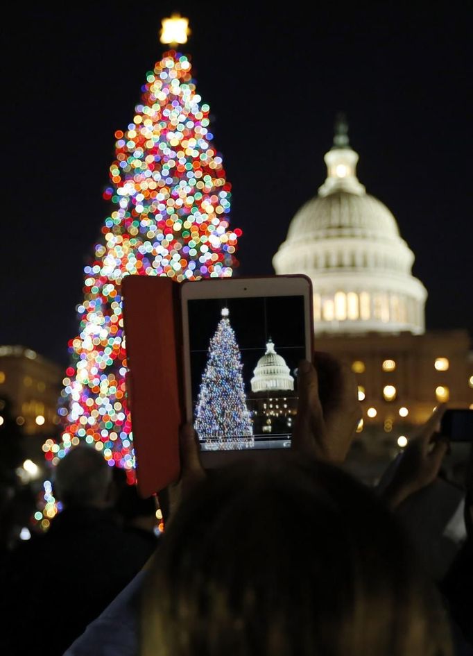 A woman takes a picture with her iPad Mini during the official lighting ceremony of the U.S. Capitol Christmas Tree in Washington December 4, 2012. REUTERS/Jason Reed (UNITED STATES - Tags: SOCIETY) Published: Pro. 4, 2012, 11:31 odp.