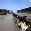 Bangladéš 2009 - děti na vrakovišti nesou rouru