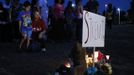 People stand behind a memorial after a vigil for victims behind the theater where a gunman opened fire on moviegoers in Aurora, Colorado July 20, 2012. A total of 71 people were shot in Friday's rampage at the Denver-area movie theater that has left 12 people dead, the local police chief said. The suspect, identified by police as James Eagan Holmes, 24, also booby-trapped his Aurora apartment with sophisticated explosives, creating a hazard for law-enforcement and bomb squad officers who swarmed to the scene. REUTERS/Shannon Stapleton (UNITED STATES - Tags: CRIME LAW) Published: Čec. 21, 2012, 3:06 dop.