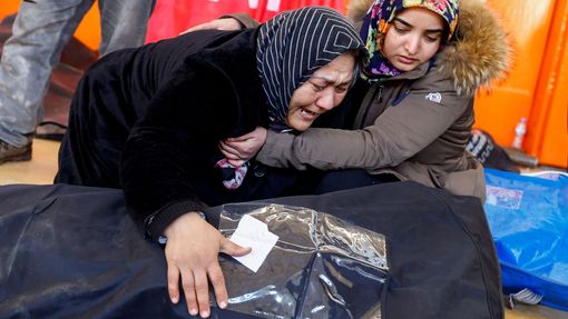 Ženy reagují u těla svého příbuzného, které je uloženo na stadionu po smrtelném zemětřesení v tureckém Kahramanmarasu.