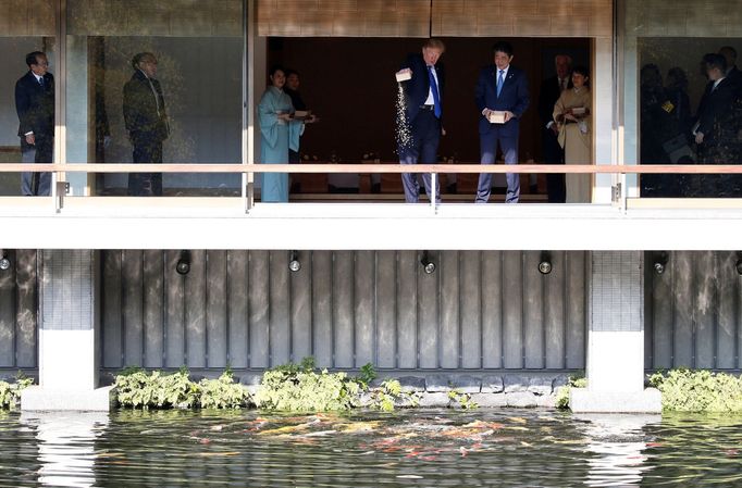 Americký prezident Donald Trump a japonský premiér Šinzó Abe krmí kapry.