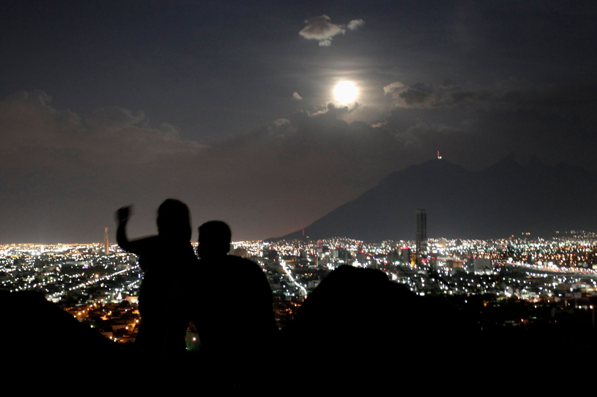 A supermoon rises while a couple takes a photo in Monterrey