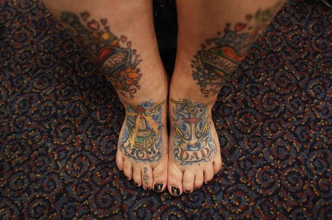 Keisha Holcomb, 31, from Fort Collins, Colorado, shows the Mom and Dad tattoos she had applied to her feet as she participates in the National Tattoo Association Convention in Cincinnati, Ohio April 13, 2012. Holcomb, the product of a military family upbringing, was 16 when she got her first tattoo and is now a budding tattoo artist herself. She wants to have a full-body tattoo eventually, with the exception of her hands, throat and head. "Try to keep it classy", she says. Picture taken April 13, 2012. REUTERS/Larry Downing (UNITED STATES - Tags: SOCIETY) ATTENTION EDITORS PICTURE 18 OF 31 FOR PACKAGE 'ADDICTED TO THE NEEDLE' TO FIND ALL PICTURES SEARCH 'ADDICTED NEEDLE' Published: Čer. 29, 2012, 12:59 odp.