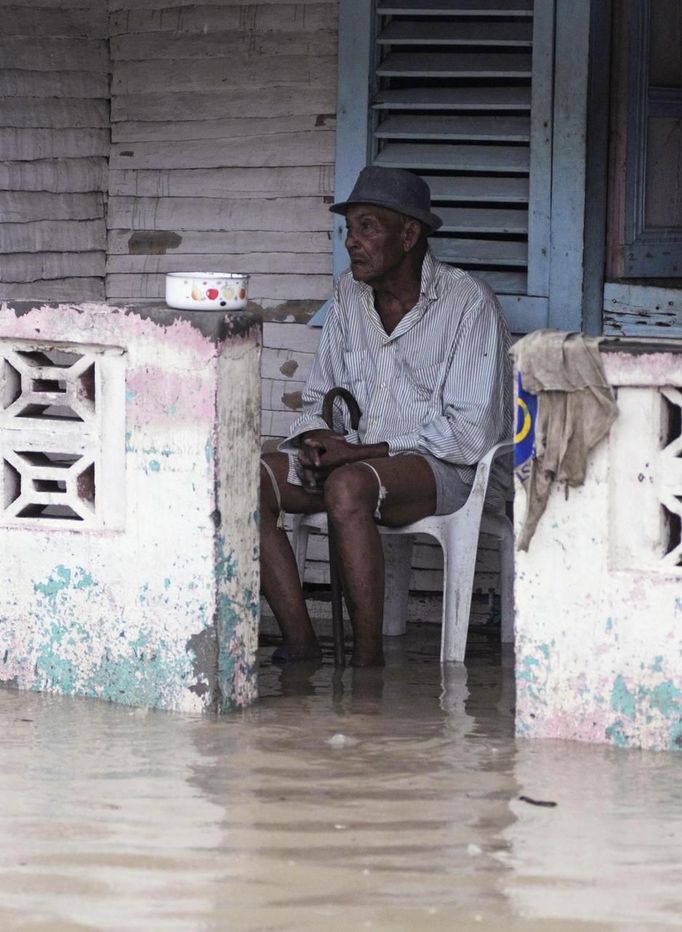 A man sits in his porch flooded by rain from Tropical Storm Isaac in Jaquimeyes, Barahona province, August 25, 2012. Tropical Storm Isaac emerged over warm Caribbean waters on Saturday slightly weaker but ready to regroup after dumping torrential rains on the Dominican Republic and Haiti. REUTERS/Ricardo Rojas (DOMINICAN REPUBLIC - Tags: DISASTER ENVIRONMENT) Published: Srp. 25, 2012, 4:51 odp.