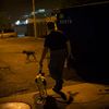 Bill leads his dog Paco, a Feist Terrier, though a vacant lot near trash dumpsters during an organized rat hunt on New York City's Lower East Side