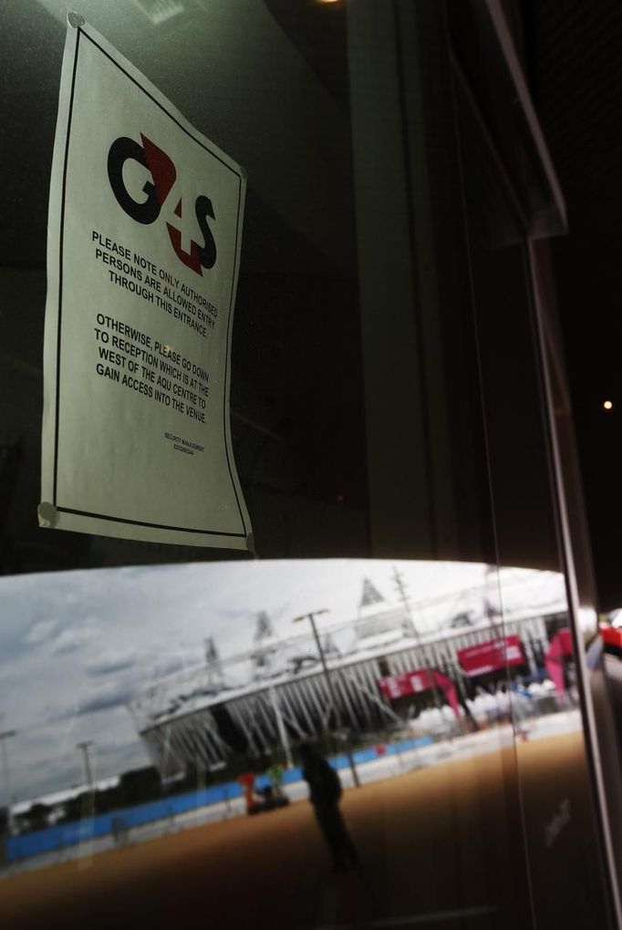 A sign for G4S security firm and a reflection of the Olympic Stadium are seen in a window in the London 2012 Olympic Park at Stratford in London July 12, 2012. Preparations for the London Olympics have put Britain's intelligence agencies under significant pressure, as the country stages its largest ever peacetime security operation, MPs said on Thursday. REUTERS/Luke MacGregor (BRITAIN - Tags: SPORT OLYMPICS MILITARY) Published: Čec. 12, 2012, 6:32 odp.