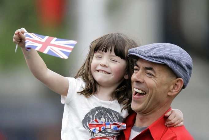 A man holding a girl waving a Union flag stands among other spectators near Parliament Square for a glimpse of Queen Elizabeth in London June 5, 2012. Four days of nationwide celebrations during which millions of people have turned out to mark the Queen's Diamond Jubilee conclude on Tuesday with a church service and carriage procession through central London. REUTERS/Kevin Coombs (BRITAIN - Tags: ROYALS SOCIETY) Published: Čer. 5, 2012, 1:29 odp.