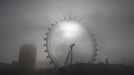 Slunce se prokousává skrze mlhu Londýna. Ráno u turistické atrakce London Eye.