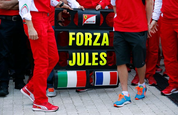 A sign in support of Marussia Formula One driver Jules Bianchi of France is seen among members of Ferrari Formula One team before the first Russian Grand Prix in Sochi Oc