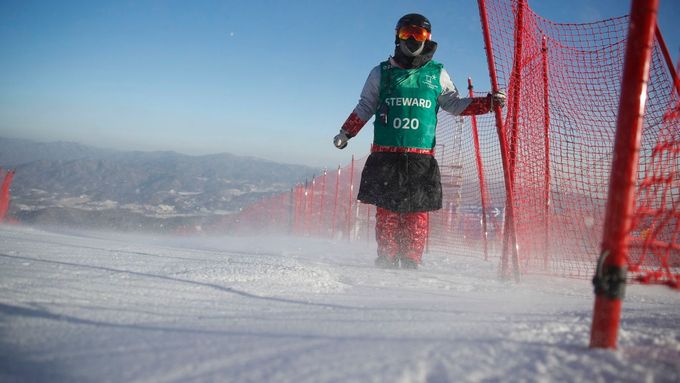 Stewardi na trati obřího slalomu se museli kvůli větru přidržovat tyčí od ochranných sítí.