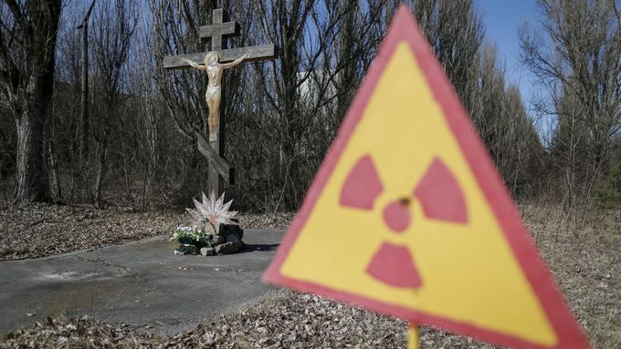 Kristus na kříži a značka upozorňující na radiaci u opuštěného města Pripjať nedaleko Černobylu.