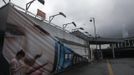 A man walks past a damaged advertisement banner after Typhoon Vicente hit Hong Kong July 24, 2012. A severe typhoon hit Hong Kong on Tuesday, disrupting business across the financial hub, with offices and the stock market to remain closed for at least part of the morning after the city raised its highest typhoon warning overnight. Seen in the background (R) is Hong Kong's International Finance Centre (IFC) building. REUTERS/Tyrone Siu (CHINA - Tags: ENVIRONMENT DISASTER) Published: Čec. 24, 2012, 2:42 dop.