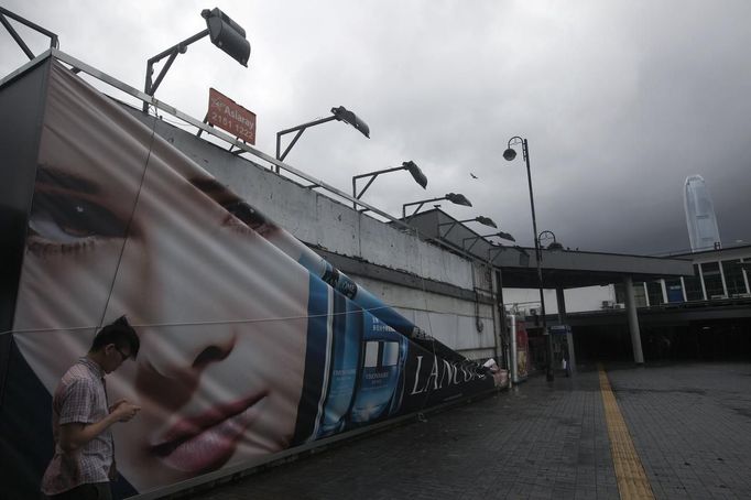 A man walks past a damaged advertisement banner after Typhoon Vicente hit Hong Kong July 24, 2012. A severe typhoon hit Hong Kong on Tuesday, disrupting business across the financial hub, with offices and the stock market to remain closed for at least part of the morning after the city raised its highest typhoon warning overnight. Seen in the background (R) is Hong Kong's International Finance Centre (IFC) building. REUTERS/Tyrone Siu (CHINA - Tags: ENVIRONMENT DISASTER) Published: Čec. 24, 2012, 2:42 dop.