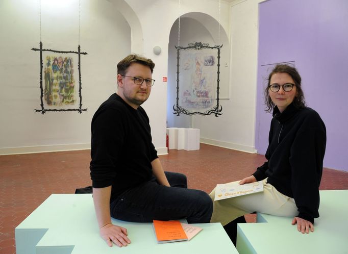 V popředí jsou umělec Zdeněk Svejkovský a kurátorka Martina Johnová, vzadu díla Jozefa Mrvy nazvaná Tokens of Desire, digitální tisk, řezaný plech, 2022.