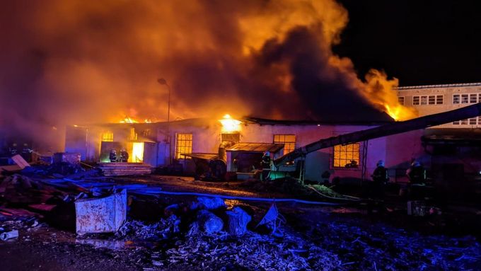 Přes 100 hasičů zasahuje od rána u požáru haly na dřevo v Čelákovicích.