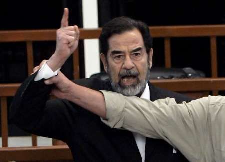 Soudní stráž se snaží zpacifikovat křičícího Saddáma Husajna, zatímco šéf tribunálu předčítá rozsudek