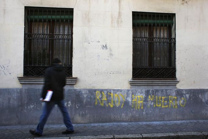 Muž prochází v Madridu kolem nápisu "Rajoy je mrtvý."