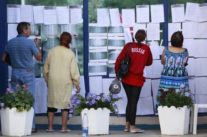 Lidé pročítají papíry s informacemi, které zde zanechali zdejší občané, aby je mohli vypátrat jejich známí.