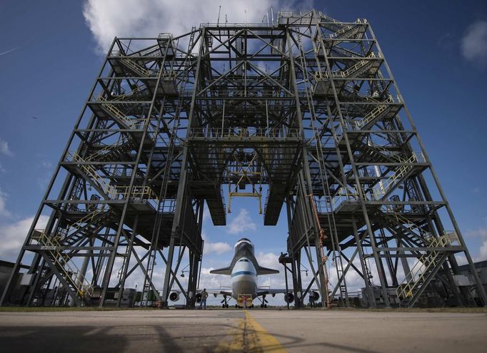 Space shuttle Endeavour, mated atop NASA's Shuttle Carrier Aircraft, is moved back into the Shuttle Mate-Demate Device at the Kennedy Space Center Shuttle Landing Facility in Cape Canaveral, Florida in this NASA handout image dated September 18, 2012. The SCA, a modified 747 jetliner, will fly Endeavour to Los Angeles where it will be placed on public display at the California Science Center. This is the final ferry flight scheduled in the Space Shuttle Program era. REUTERS/NASA/Bill Ingalls/Handout (UNITED STATES - Tags: SCIENCE TECHNOLOGY) FOR EDITORIAL USE ONLY. NOT FOR SALE FOR MARKETING OR ADVERTISING CAMPAIGNS. THIS IMAGE HAS BEEN SUPPLIED BY A THIRD PARTY. IT IS DISTRIBUTED, EXACTLY AS RECEIVED BY REUTERS, AS A SERVICE TO CLIENTS Published: Zář. 18, 2012, 10:45 odp.