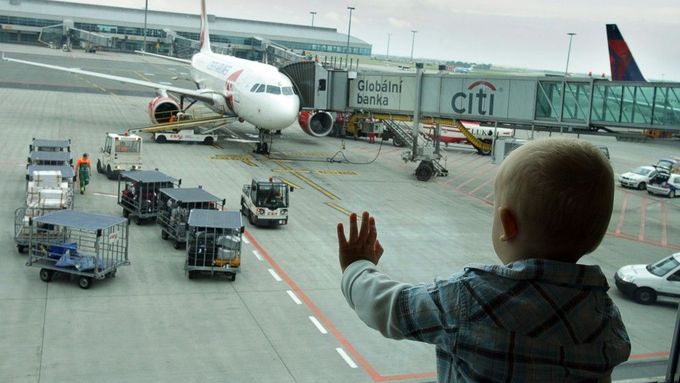 Malé dítě pozoruje z jednoho z odbavovacích tubusů ruzyňského letiště stroj připravený k odletu.