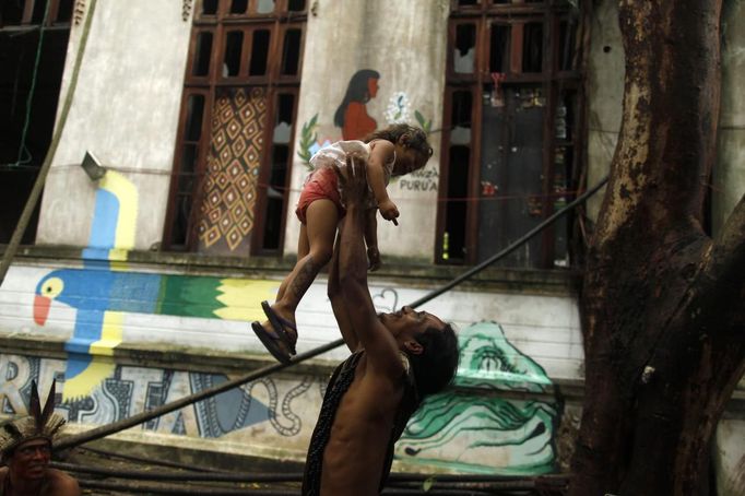 A Brazilian Indian man plays with an Indian girl at the Brazilian Indian Museum in Rio de Janeiro, March 18, 2013. A native Indian community of around 30 individuals who have been living in the abandoned Indian Museum since 2006, were summoned to leave the museum in 72 hours by court officials since last Friday, local media reported. The group is fighting against the destruction of the museum, which is next to the Maracana Stadium, to make way for a planned 10,000-car parking lot in preparation for the 2014 Brazil World Cup. REUTERS/Pilar Olivares (BRAZIL - Tags: SOCIETY CIVIL UNREST) Published: Bře. 18, 2013, 10:39 odp.