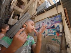Palestinští chlapci si hrají v uprchlickém táboře před plakáty s fotografiemi radikálů.