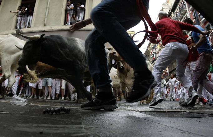 Runners sprint alongside Miura fighting bulls at the Estafeta corner on the the second day of the running of the bulls in Pamplona July 8 2012. Various runners suffered light injuries in a run that lasted two minutes and twenty-eight seconds, according to local media. REUTERS/Joseba Etxaburu (SPAIN - Tags: ANIMALS SOCIETY TPX IMAGES OF THE DAY) Published: Čec. 8, 2012, 8:39 dop.