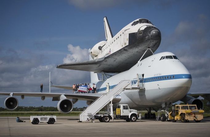 Workers pose for a photograph on the wing of NASA's Shuttle Carrier Aircraft, (SCA) with the space shuttle Endeavour mated on top, at the Kennedy Space Center, Shuttle Landing Facility in Cape Canaveral, Florida in this NASA handout September 18, 2012. The SCA, a modified 747 jetliner, will fly Endeavour to Los Angeles where it will be placed on public display at the California Science Center. This is the final ferry flight scheduled in the Space Shuttle Program era. REUTERS/NASA/Bill Ingalls/Handout (UNITED STATES - Tags: SCIENCE TECHNOLOGY) FOR EDITORIAL USE ONLY. NOT FOR SALE FOR MARKETING OR ADVERTISING CAMPAIGNS. THIS IMAGE HAS BEEN SUPPLIED BY A THIRD PARTY. IT IS DISTRIBUTED, EXACTLY AS RECEIVED BY REUTERS, AS A SERVICE TO CLIENTS Published: Zář. 18, 2012, 10:54 odp.