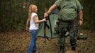 Brianna, 9, of the North Florida Survival Group hands an AK-47 rifle to Jim Foster, 57, the group's leader, before heading out to conduct enemy contact drills during a field training exercise in Old Town, Florida, December 8, 2012. The group trains children and adults alike to handle weapons and survive in the wild. The group passionately supports the right of U.S. citizens to bear arms and its website states that it aims to teach "patriots to survive in order to protect and defend our Constitution against all enemy threats". Picture taken December 8, 2013. REUTERS/Brian Blanco (UNITED STATES - Tags: SOCIETY POLITICS TPX IMAGES OF THE DAY) ATTENTION EDITORS: PICTURE 2 20 FOR PACKAGE 'TRAINING CHILD SURVIVALISTS' SEARCH 'FLORIDA SURVIVAL' FOR ALL Published: Úno. 22, 2013, 1:06 odp.