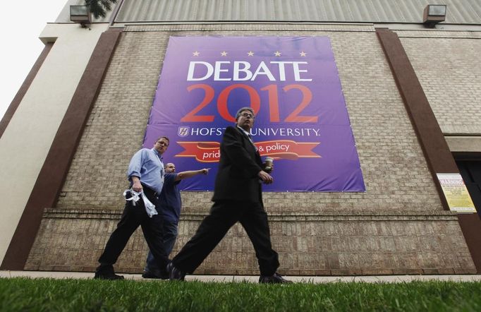 Pedestrians walk past a large debate sign hanging from a building during preparations for Tuesday's U.S. presidential debate at Hofstra University in Hempstead, New York, October 15, 2012. REUTERS/Lucas Jackson (UNITED STATES - Tags: POLITICS USA PRESIDENTIAL ELECTION ELECTIONS) Published: Říj. 15, 2012, 11:20 odp.