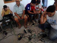Chilané v Santiagu se snaží dobít své telefony na jednom z mála míst čtvrti, kde funguje elektřina.