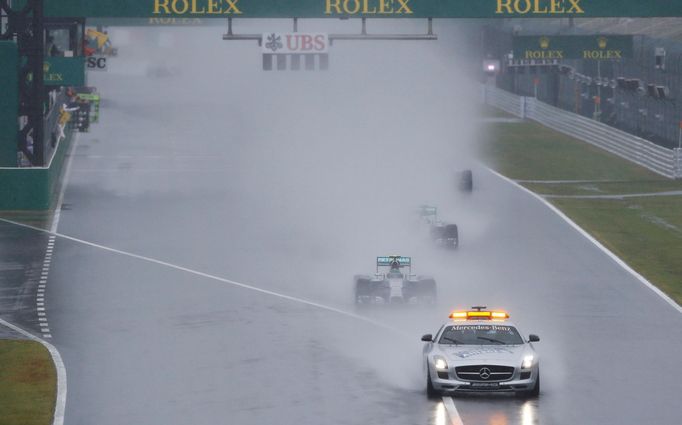 Mercedes Formula One driver Nico Rosberg of Germany leads team mate Lewis Hamilton of Britain behind a safety car as they start the first lap of the rain-affected Japanes