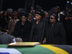 Winnie Mandela, někdejší žena exprezidenta (vlevo) a Graca Machel, vdova po Mandelovi (uprostřed) stojí u jeho rakve na pohřbu v Qunu.