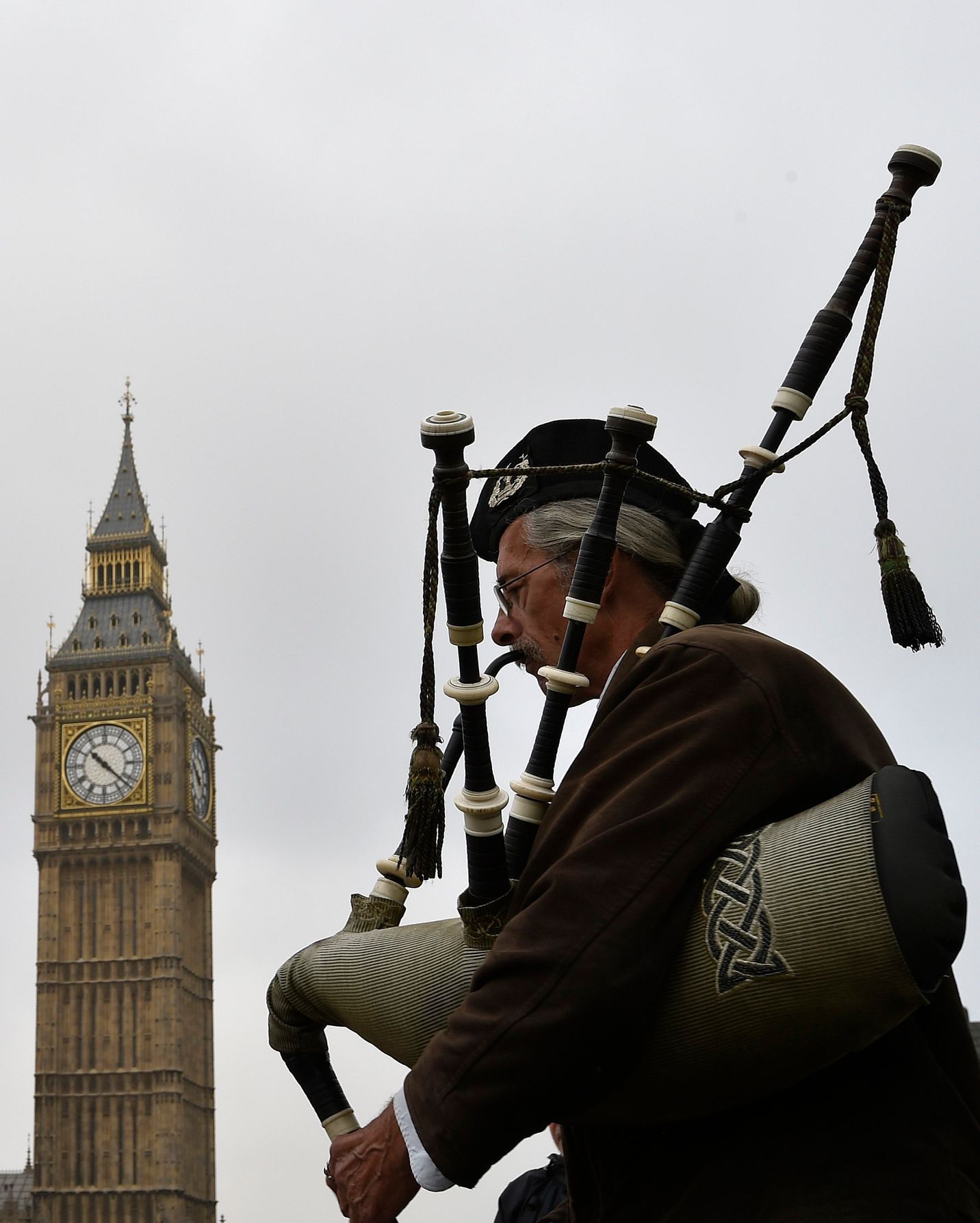 A street performer plays the Scottish bagpipes dressed in traditional Scottish attire on Westminster Bridge in London