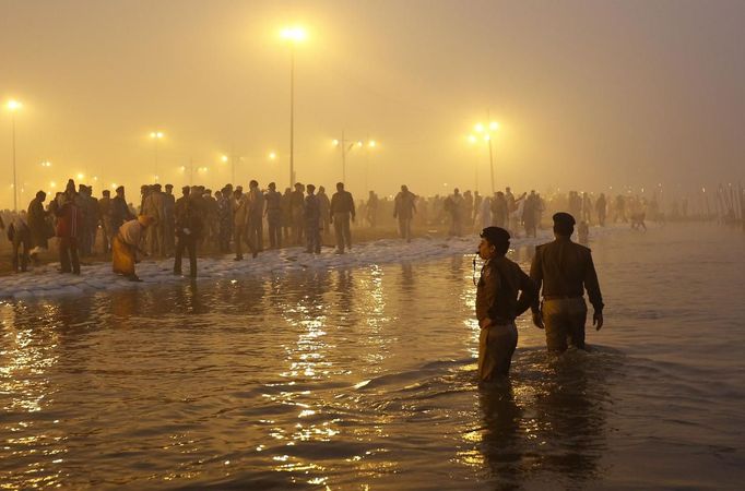 Policemen stand in the waters of the Ganges river to maintain order during the first "Shahi Snan" (grand bath) at the ongoing "Kumbh Mela", or Pitcher Festival, in the northern Indian city of Allahabad January 14, 2013. Upwards of a million elated Hindu holy men and pilgrims took a bracing plunge in India's sacred Ganges river to wash away lifetimes of sins on Monday, in a raucous start to an ever-growing religious gathering that is already the world's largest. REUTERS/Ahmad Masood (INDIA - Tags: RELIGION SOCIETY) Published: Led. 14, 2013, 2:01 odp.