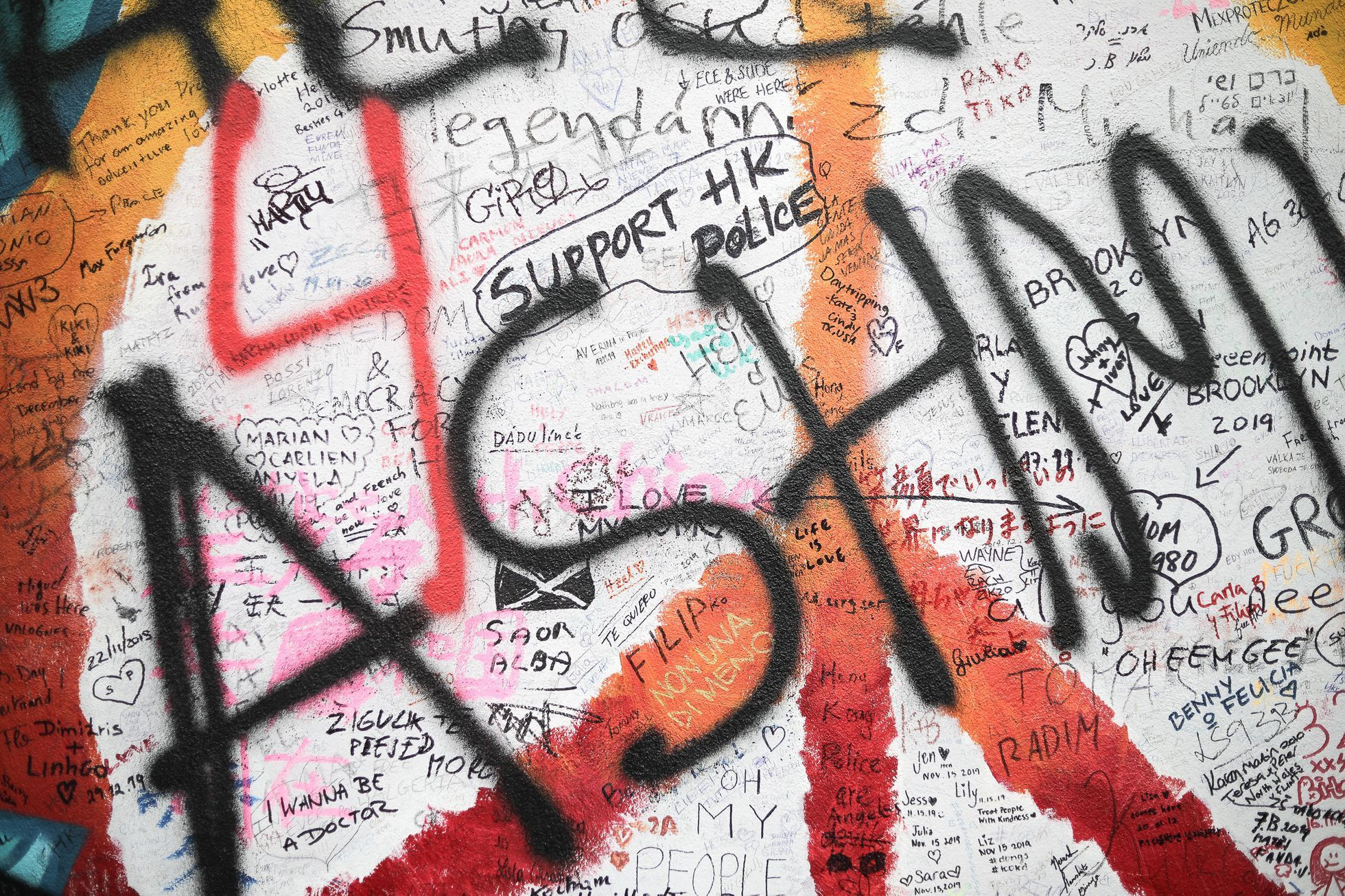 Lennonova zeď po třech měsících od malování - turisté, graffiti