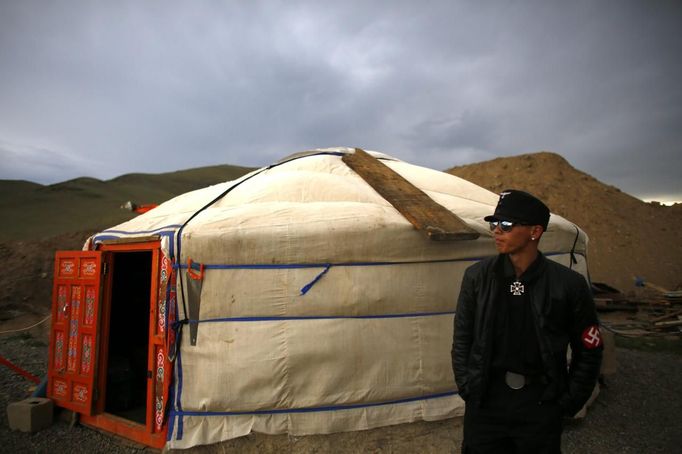 A member of the Mongolian neo-Nazi group Tsagaan Khass stands next to a 'ger', a traditional Mongolian tent, at a quarry, where they questioned a worker, southwest of Ulan Bator June 23, 2013. The group has rebranded itself as an environmentalist organisation fighting pollution by foreign-owned mines, seeking legitimacy as it sends Swastika-wearing members to check mining permits. Over the past years, ultra-nationalist groups have expanded in the country and among those garnering attention is Tsagaan Khass, which has recently shifted its focus from activities such as attacks on women it accuses of consorting with foreign men to environmental issues, with the stated goal of protecting Mongolia from foreign mining interests. This ultra-nationalist group was founded in the 1990s and currently has 100-plus members. Picture taken June 23, 2013. REUTERS/Carlos Barria (MONGOLIA - Tags: SOCIETY POLITICS TPX IMAGES OF THE DAY) ATTENTION EDITORS: PICTURE 24 OF 25 FOR PACKAGE 'MONGOLIA'S ENVIRONMENTAL NEO-NAZIS'. TO FIND ALL IMAGES SEARCH 'TSAGAAN KHASS' Published: Čec. 2, 2013, 9:58 dop.