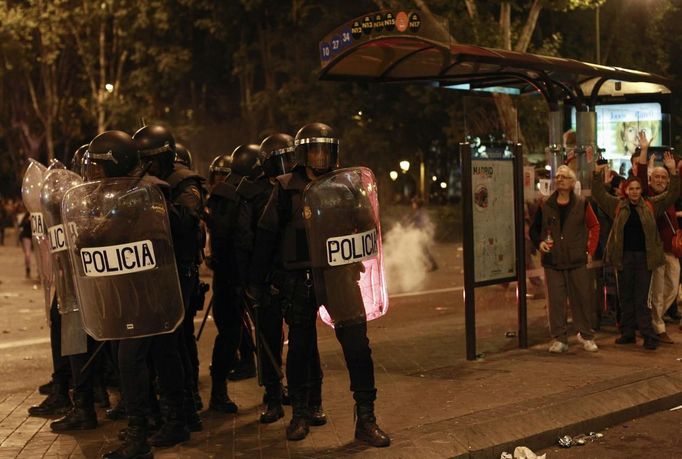 Riot police regroup as demonstrators raise their hands outside the Spanish parliament in Madrid, September 25, 2012. Protesters clashed with police in Spain's capital on Tuesday as the government prepares a new round of unpopular austerity measures for the 2013 budget that will be announced on Thursday. REUTERS/Susana Vera (SPAIN - Tags: CIVIL UNREST POLITICS BUSINESS) Published: Zář. 25, 2012, 8:33 odp.