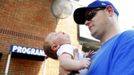 Cary McLaughlin holds his 2-month-old son Jack under the misting fans while attending a MLB National League baseball game between the Atlanta Braves and Washington Nationals at Turner Field in Atlanta, Georgia June 30, 2012. A record breaking heatwave has covered most of the country, with temperatures expected to reach 105 degrees Fahrenheit (41 degrees Celsius) in Atlanta. REUTERS/Tami Chappell (UNITED STATES - Tags: SOCIETY SPORT BASEBALL ENVIRONMENT) Published: Čer. 30, 2012, 10:55 odp.