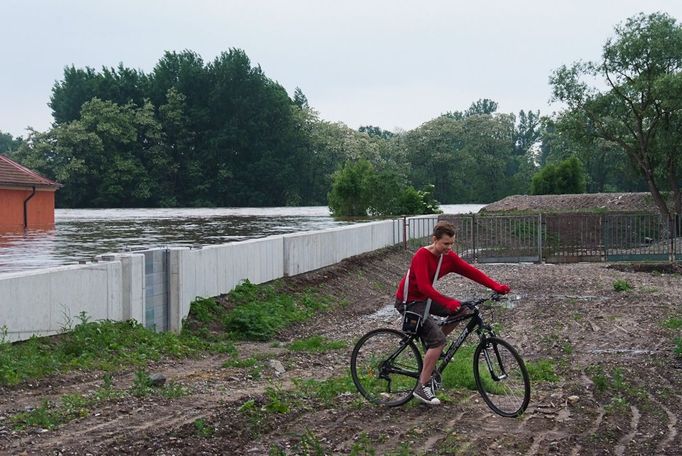 Kdyby tu nebyla tato hráz, tak by tento mladík na kole povodňové vlně asi neujel. Ocitnul by se ve smrtelném nebezpečí.