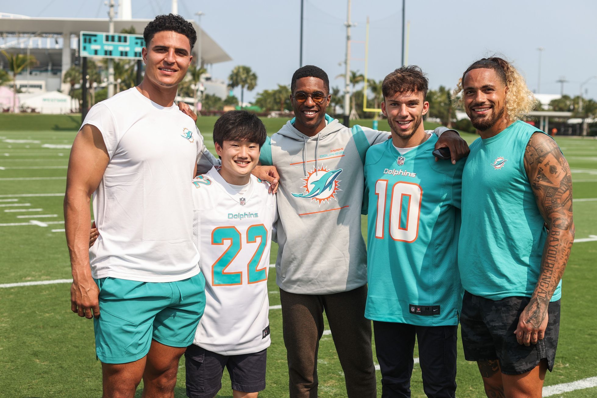 Pierre Gasly a Juki Cunoda z týmu AlphaTauri s hráči týmu NFL Miami Dolphins ve VC Miami formule 1 2022