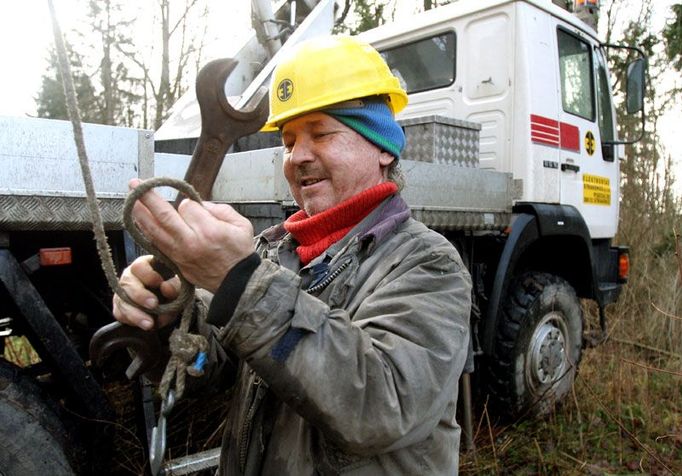 Vedle stromů a lesů zanechala vichřice velké škody na elektrickém vedení. Václav Šalát upevňuje klíč na kladku, aby jej mohl poslat kolegům nahoře na plošině. Zaměstnanci Elektrostavu Strakonice opravovali vedení u Zvíkovského hradu.